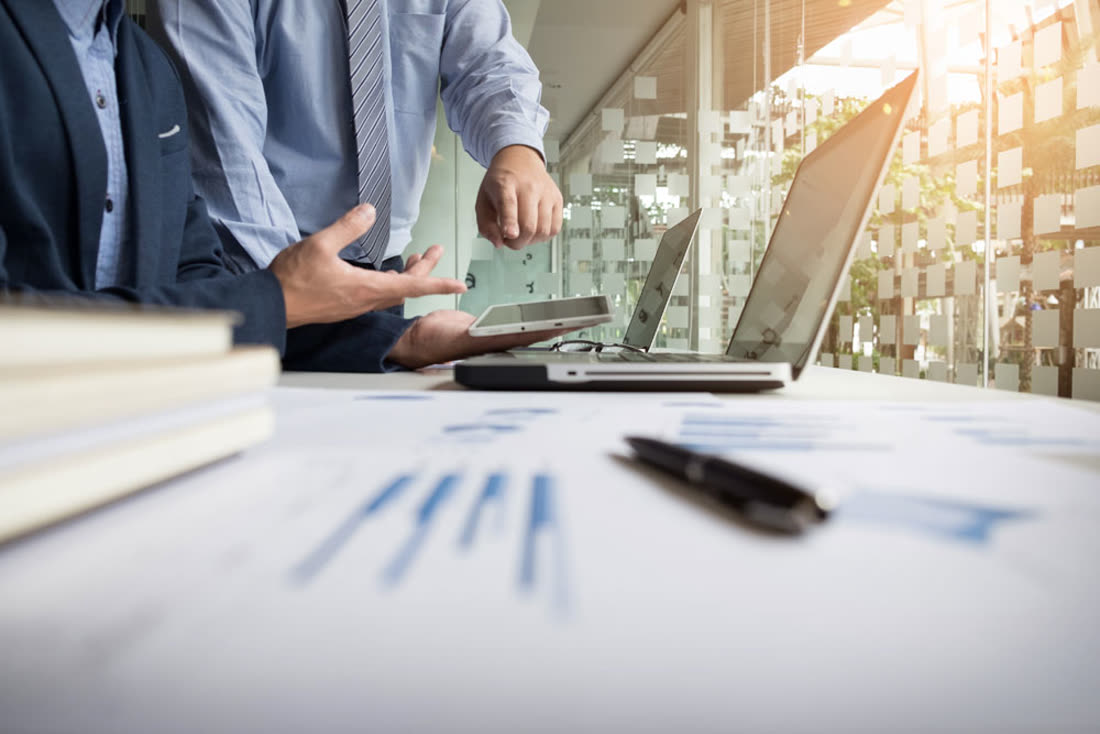 Advisor pointing out figures on a laptop screen during a client review